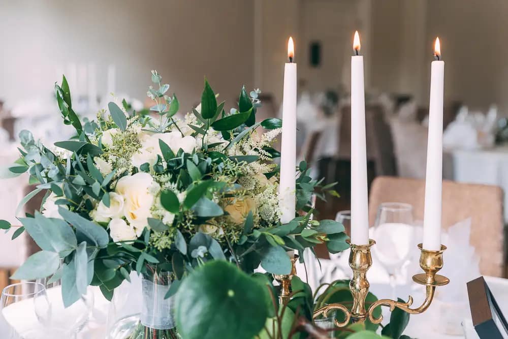 Dukning vid bröllop med gröna växter och levande ljus