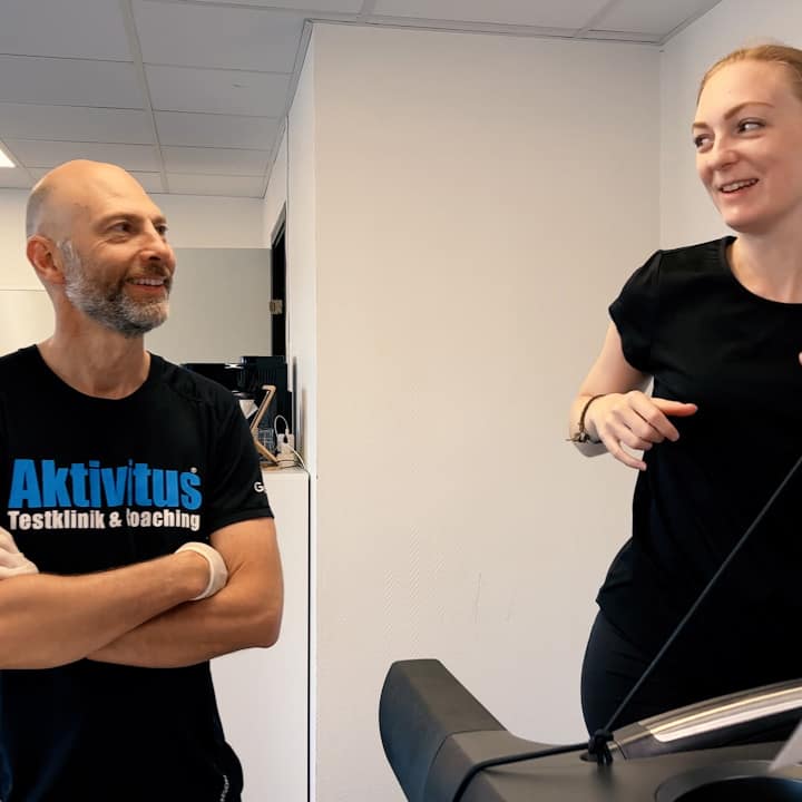 En man med Aktivitus-logga på tröjan och en kvinna som springer på ett löpband och ler.